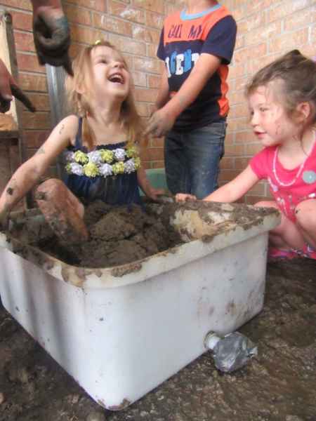girl sitting in a bin o mud on mud day